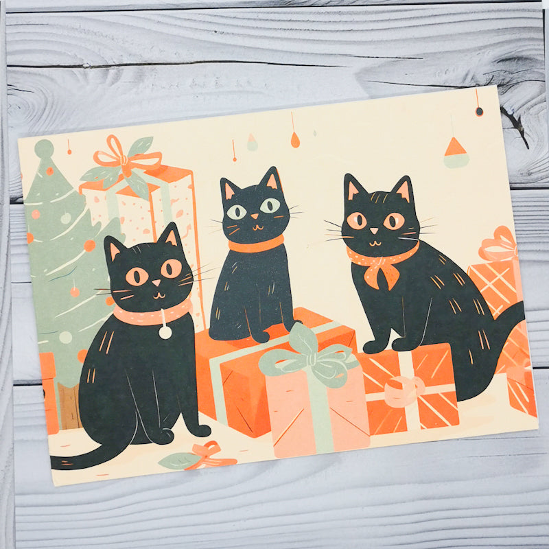 Greeting card with three black cats on about to open Christmas presents, the cats are all cute and the card is high quality and well printed, the card would be perfect for a cat lover or black cat owner at Christmas