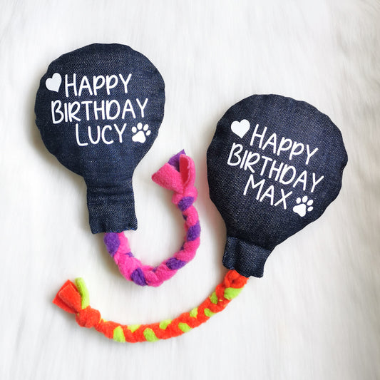 Picture shows two denim dog birthday balloons, one with a pink and purple fleece rope and the other with a green and orange one