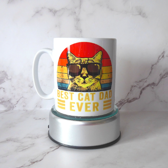 a glossy white ceramic mug which says "Best Cat Dad Ever" with a cat wearing sunglasses on, great gift for cat dads