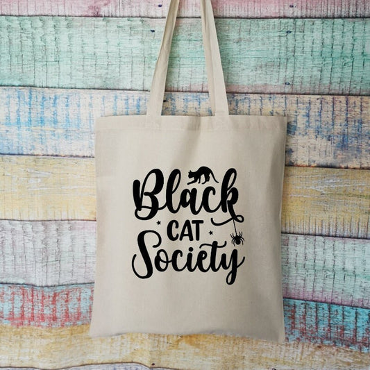 A tote bag in the colour natural which says black cat society on it, the tote bag is a great gift for any black cat owner 