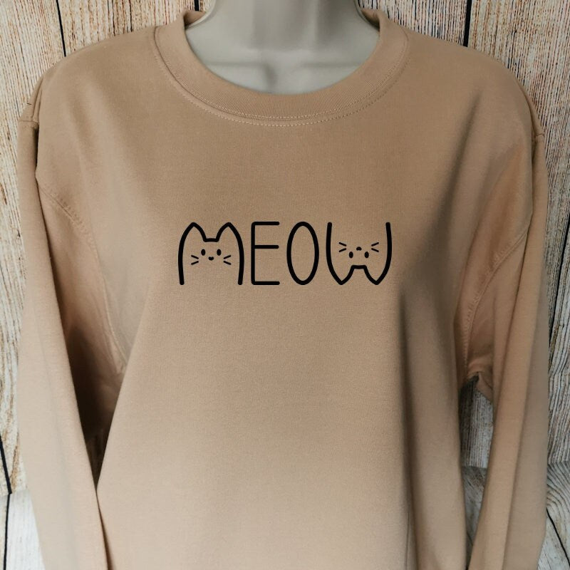 a sweatshirt for cat lovers in the colour nude with the word meow on with the m and w being two cats