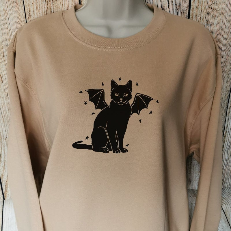 a sweatshirt in the colour nude for horror lovers and cat lovers alike which has a vampire cat on with little bat wings