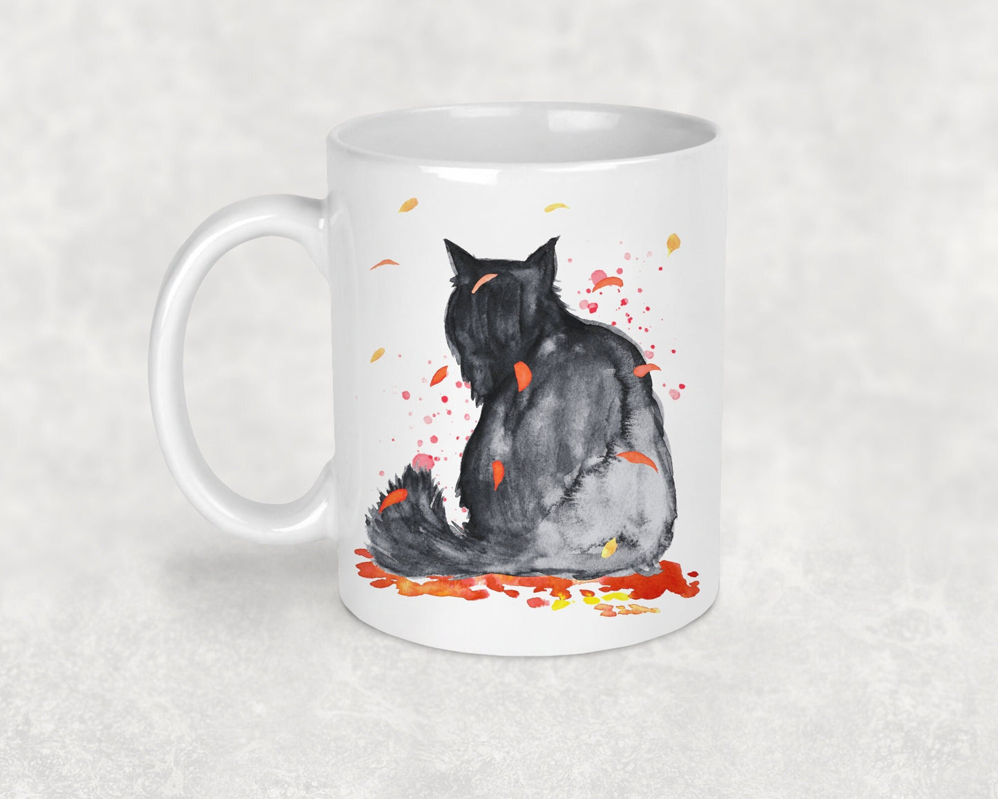 a glossy white ceramic mug with a picture of a fluffy black cat surrounded by autumn leaves, perfect mug for your hot chocolates and great gifts for cat lovers