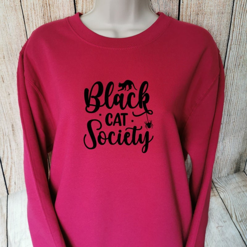 a sweatshirt in the colour cranberry which has the words black cat society on, the sweatshirt is perfect for black cat lovers